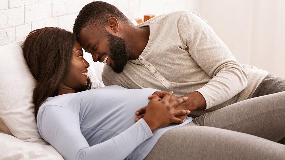 Man and pregnant woman in bed together