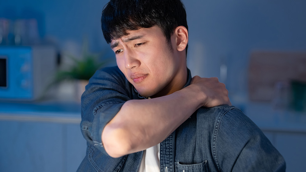 asian businessman overtime work and feel shoulder pain at home