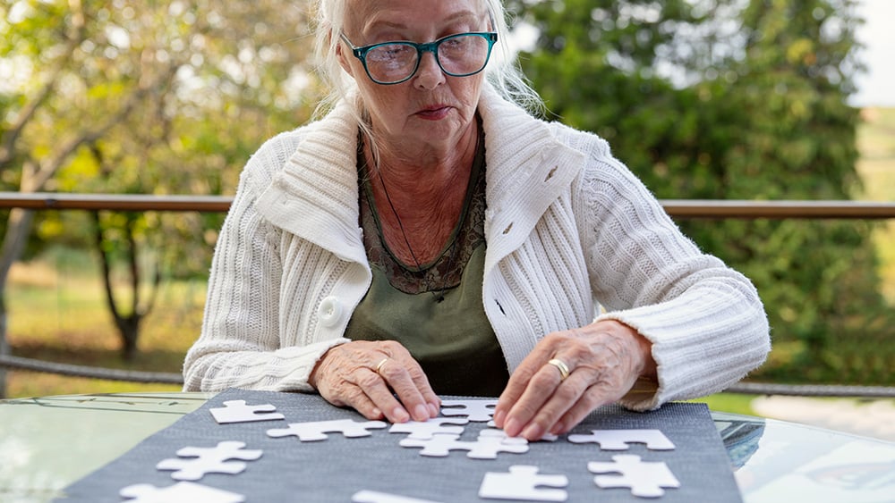 Older white woman putting puzzle together outdoors