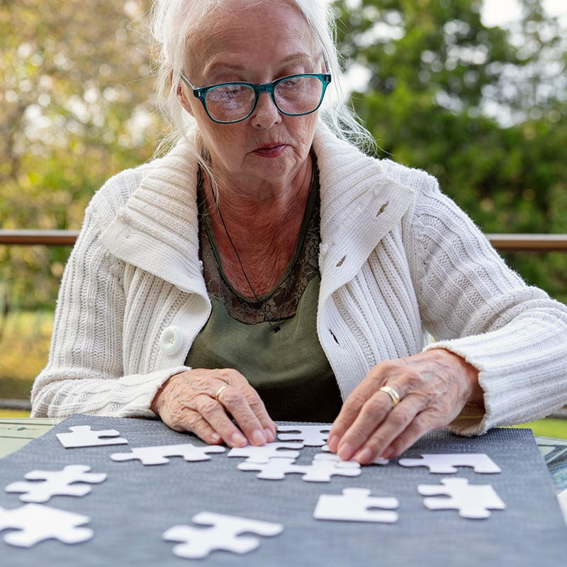 Older white woman putting puzzle together outdoors