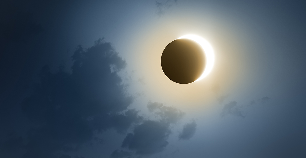 Solar Eclipse with dark blue sky and clouds