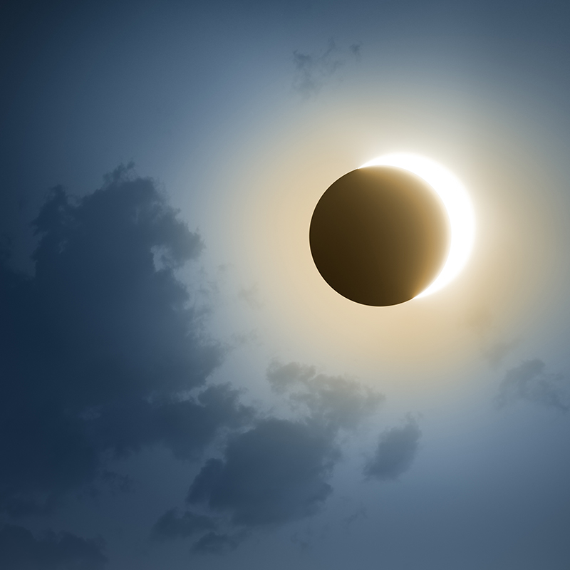 Solar Eclipse with dark blue sky and clouds