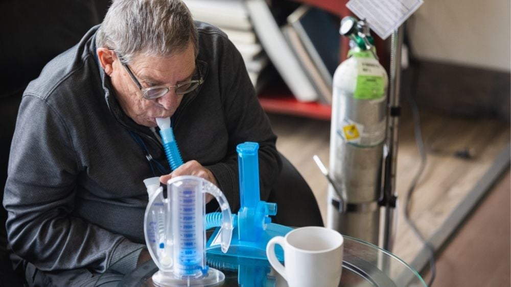 Older man using spirometer