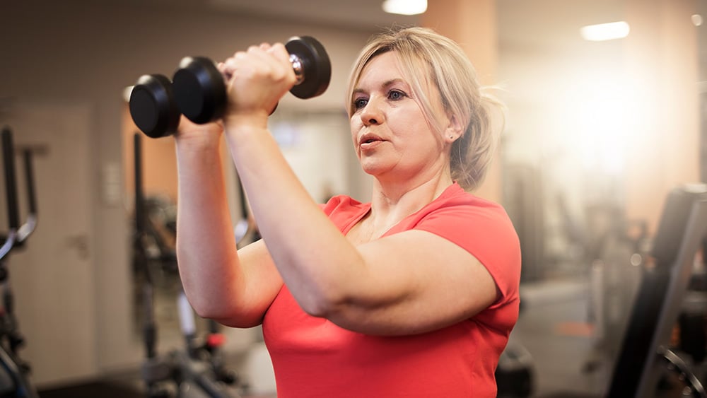 Woman in red shirt lifting weights