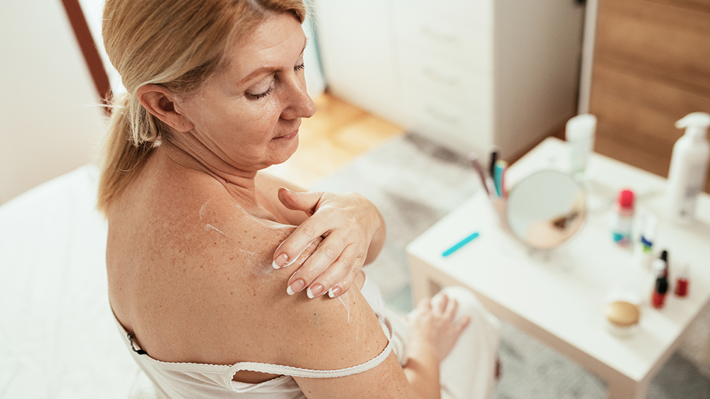Portrait of healthy mature woman with blond hair at home, enjoying beauty treatment