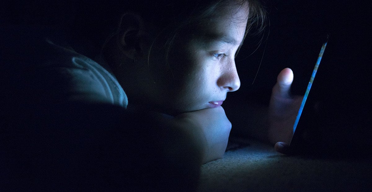 Teenager sending email from smart phone in her bed, Typing text message on smartphone. young cell phone addict teen awake at night in bed using smartphone for chatting