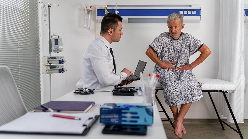 Male doctor listens intently to his senior male patient