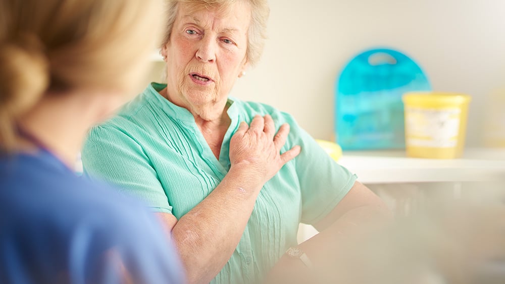 a senior female patient sits and chats to a female doctor who we see from behind