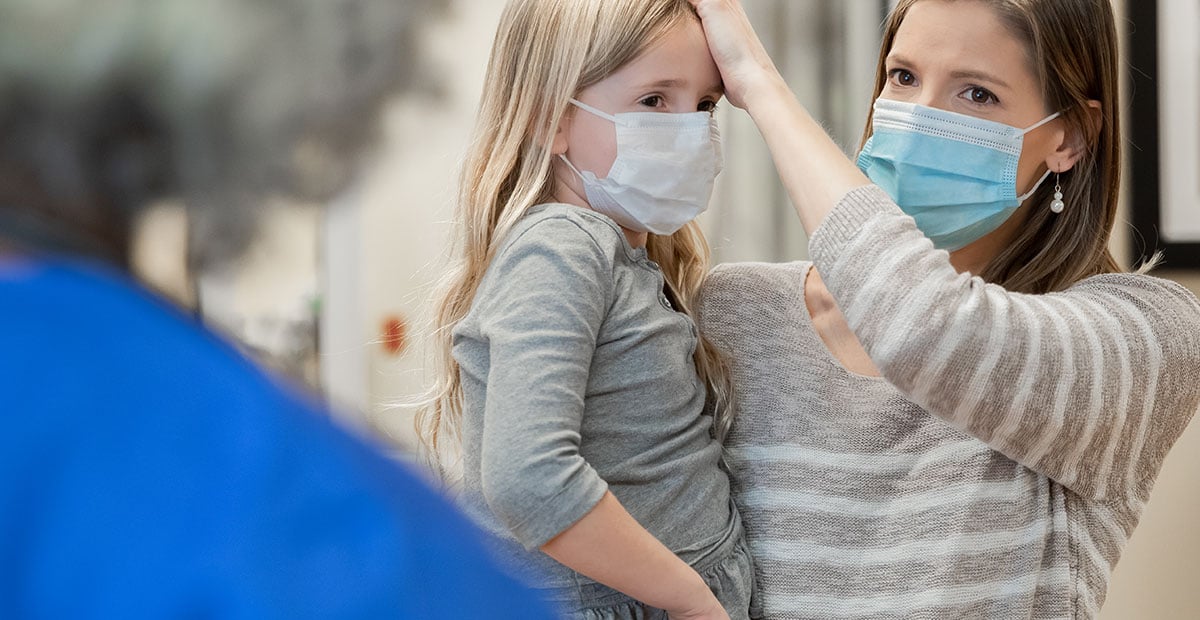 Mother explains young daughter's fever and symptoms to a pediatrician at hospital