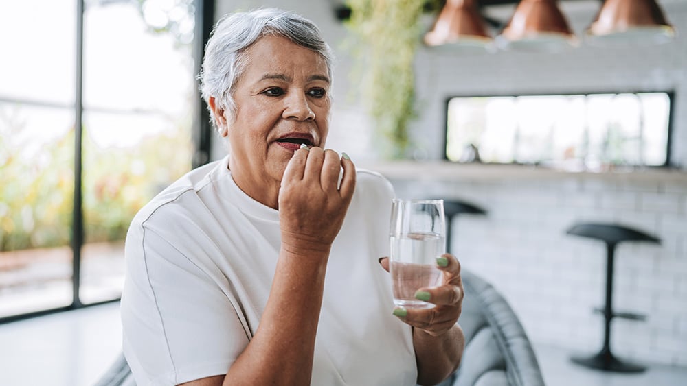 Senior woman self-medicating with medicine at home