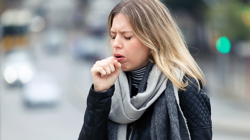 Shot of illness young woman coughing in the street