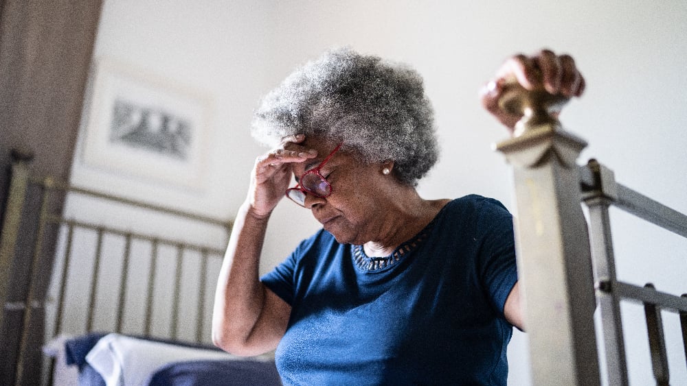 An older Black woman puts her hand on her head  suggesting she is dizzy