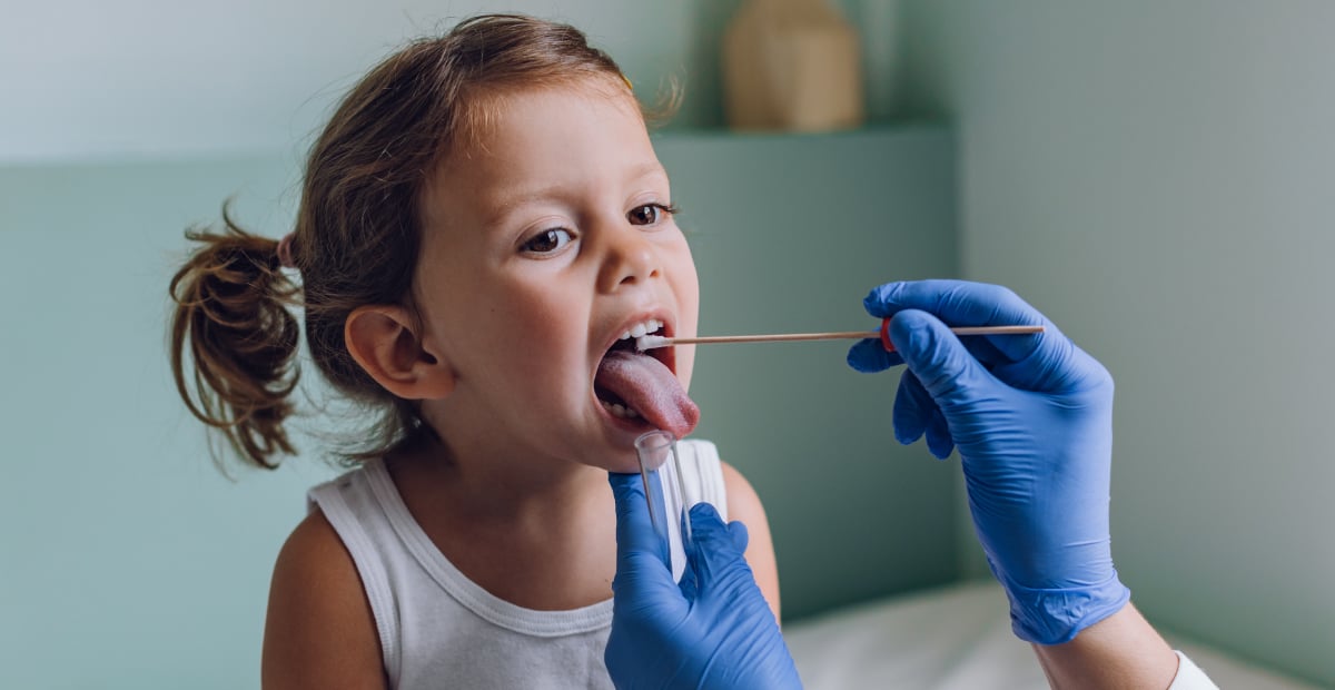 A young White girl gets a throat swab from a physician