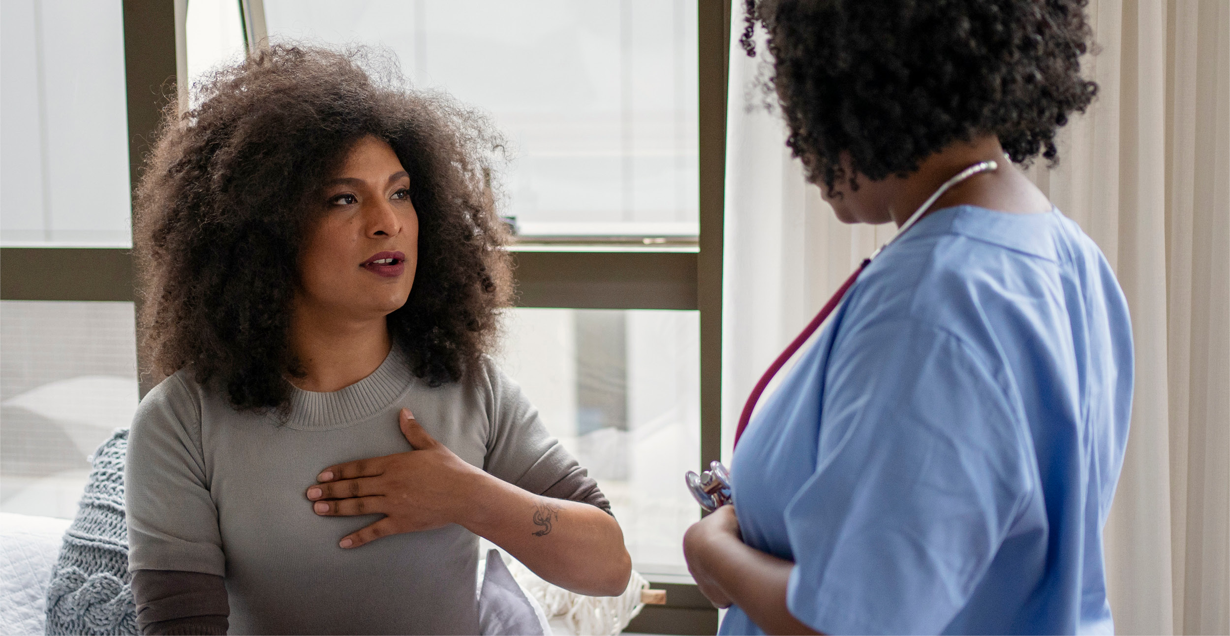A middle aged black woman talks with a black healthcare provider in a primary care provider's office