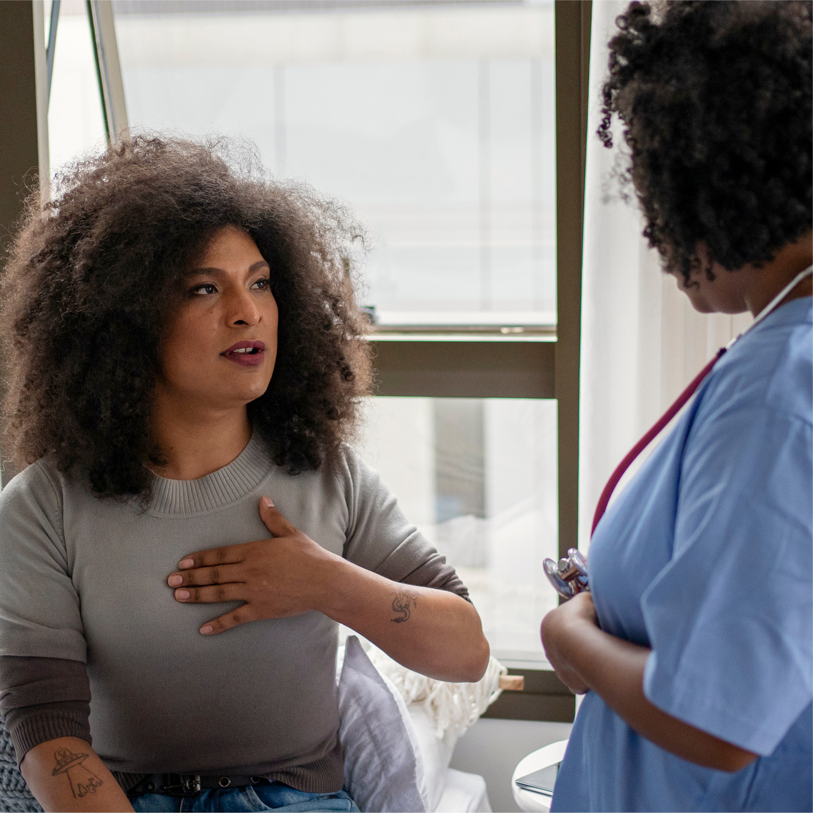 A middle aged black woman talks with a black healthcare provider in a primary care provider's office