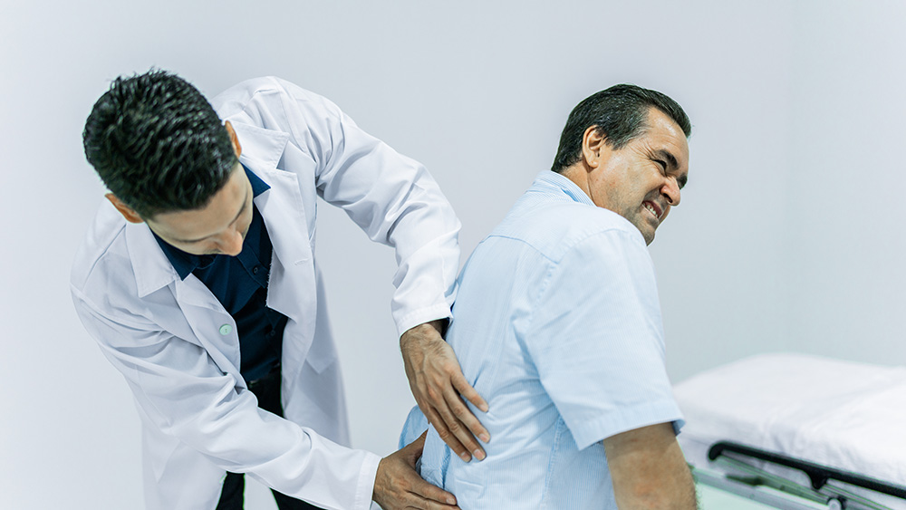 Physician checking man's back pain