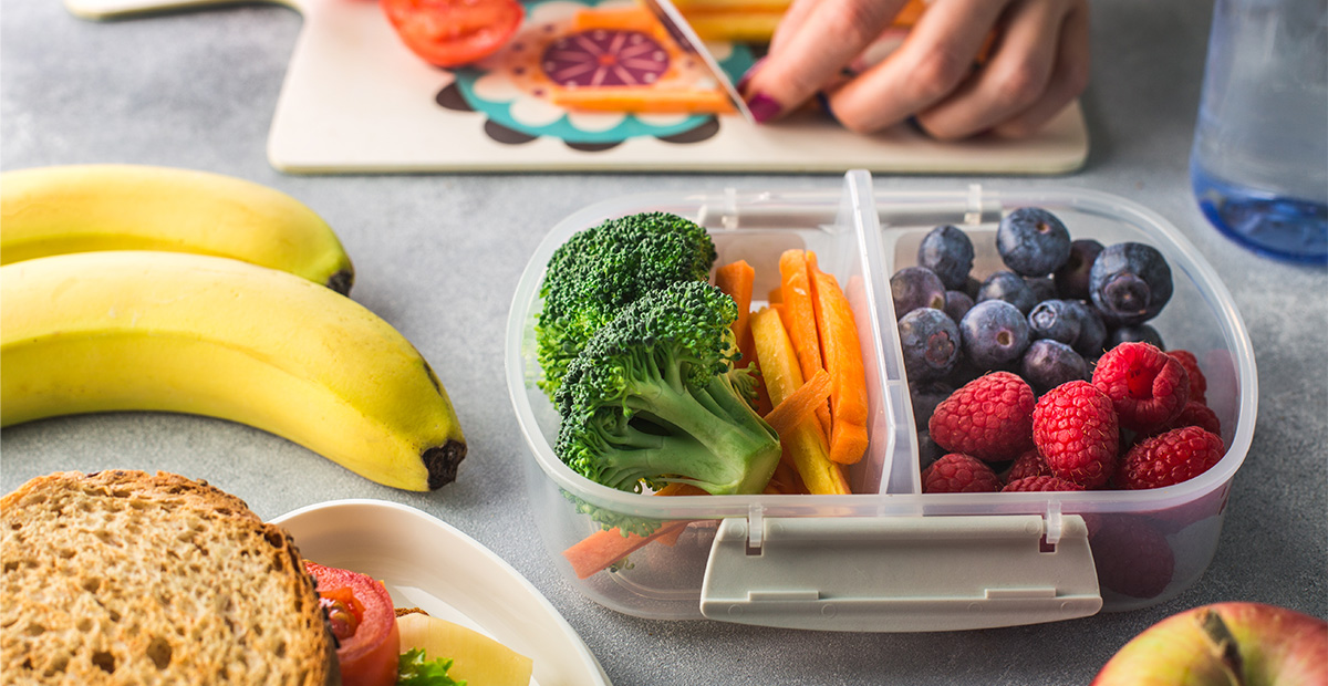 Parent puts vegetables and fruit into school lunch