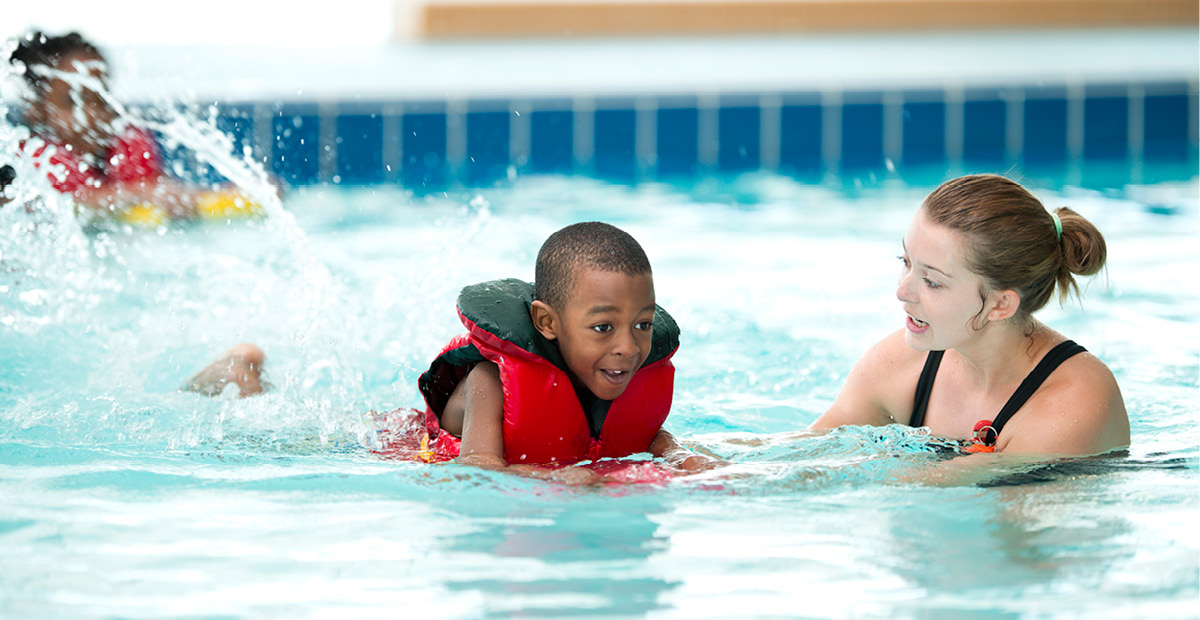 A boy swimming in a pool with a life jacket
