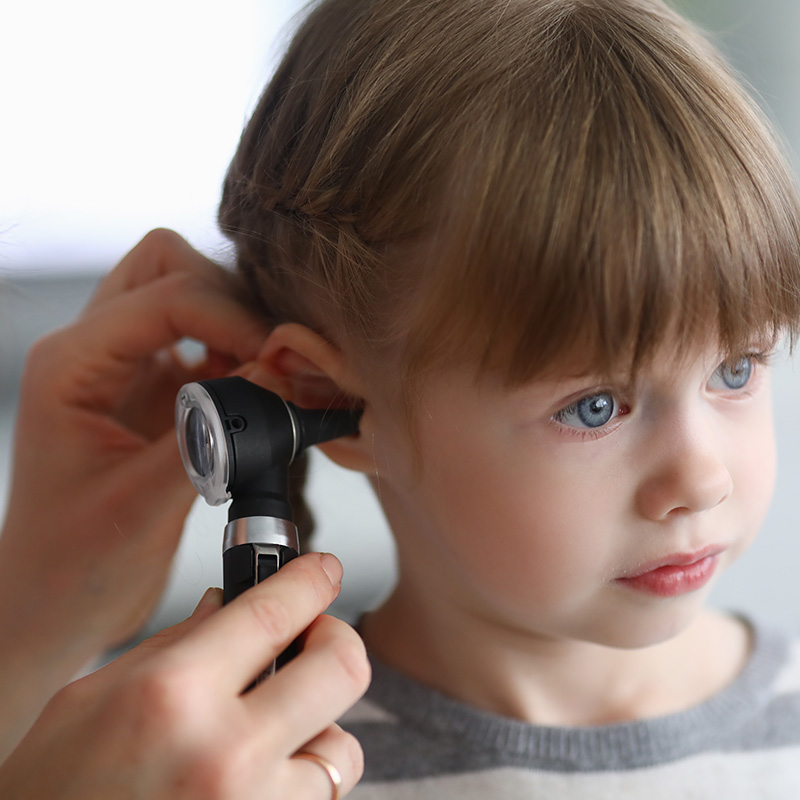 Otorhinolaryngologist examines little girl's ear with otoscope
