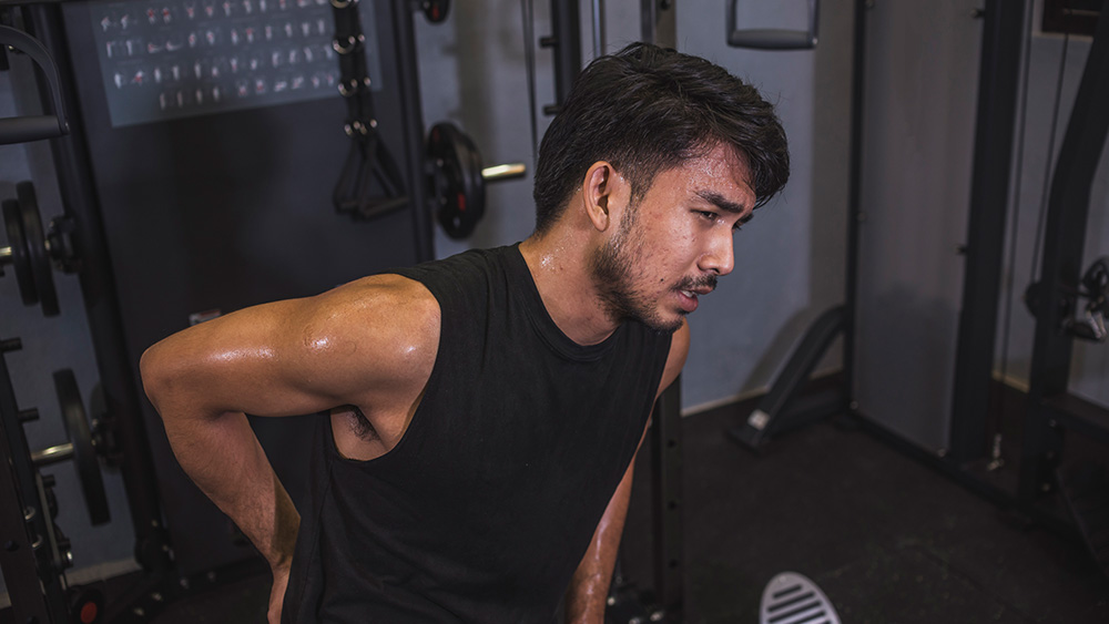 Man in weight room holding back in pain