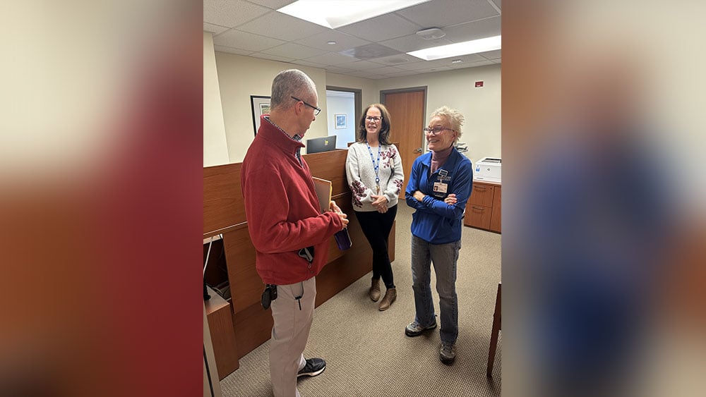 White patient smiles while talking with two female providers