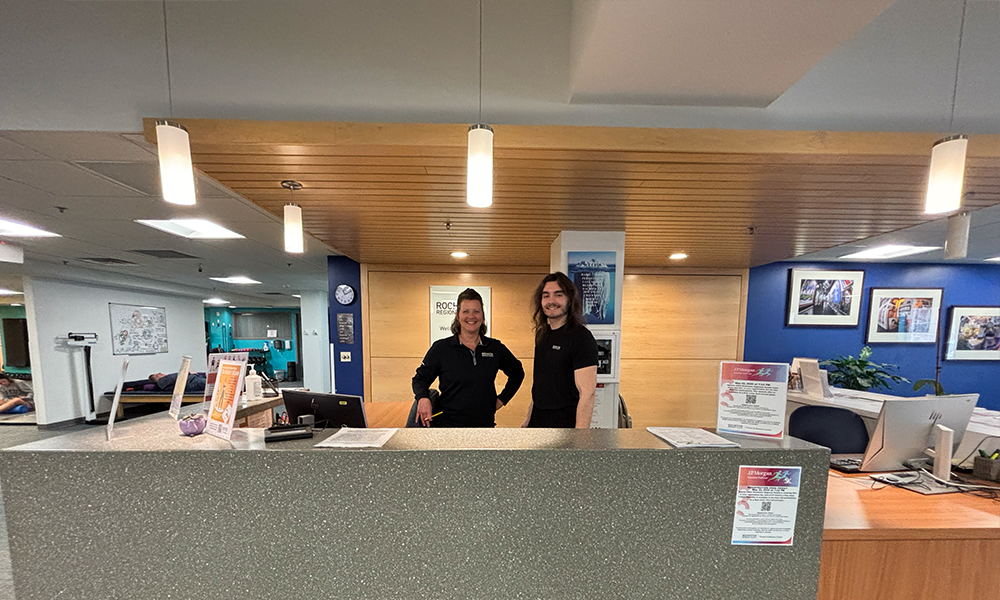Two staff members stand behind the front desk