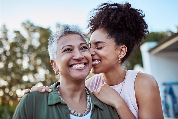Two women smile and laugh together outside