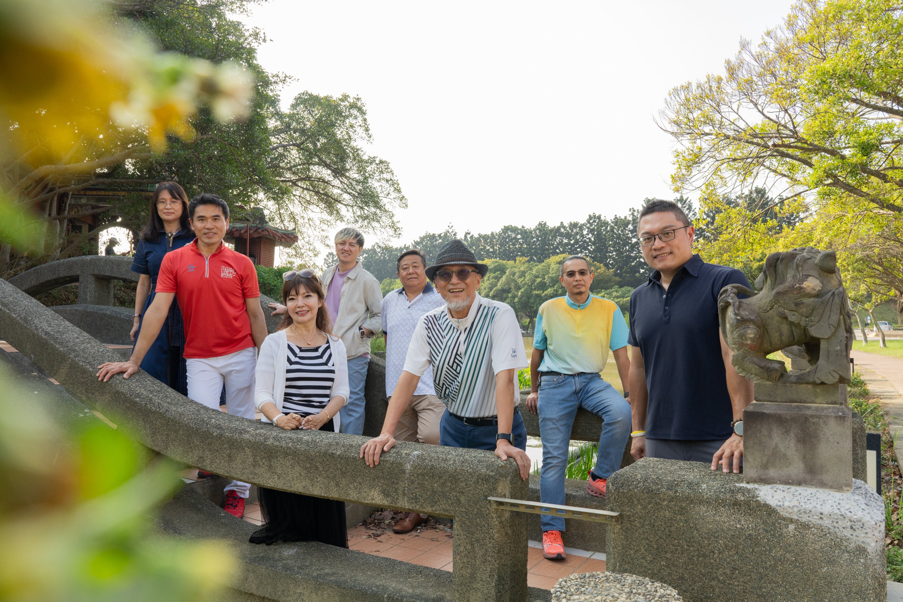 Un groupe de membres du Rotary se tenant côte à côte sur un pont ou une passerelle dans un parc en plein air
