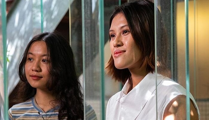 Two women from the Rotaract Club of One Million Lives Saigon stand together behind metal bars