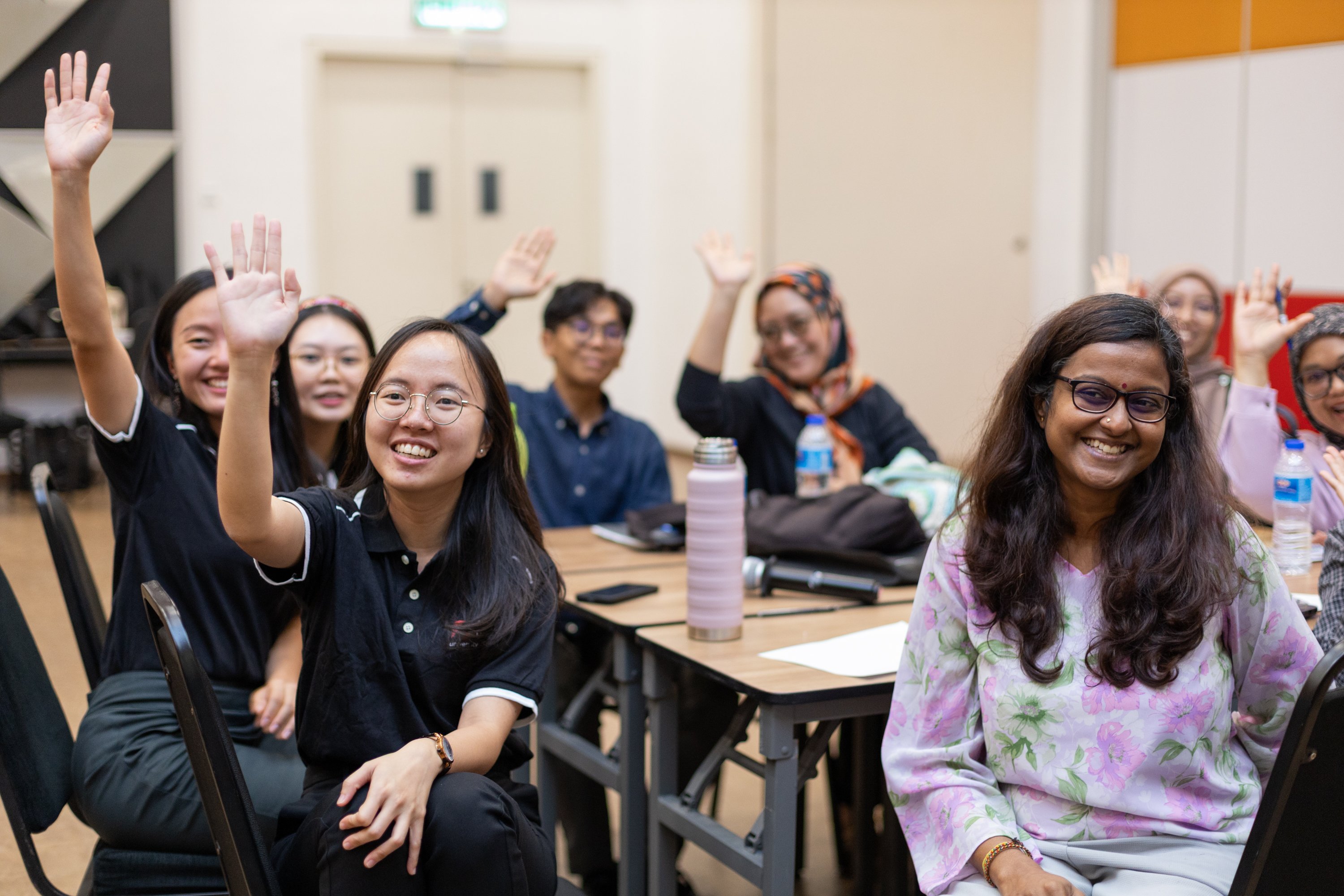 Participants in a classroom at HELP University in Kuala Lumpur raise their hands during Rotary-led psychological first aid training, May 2025