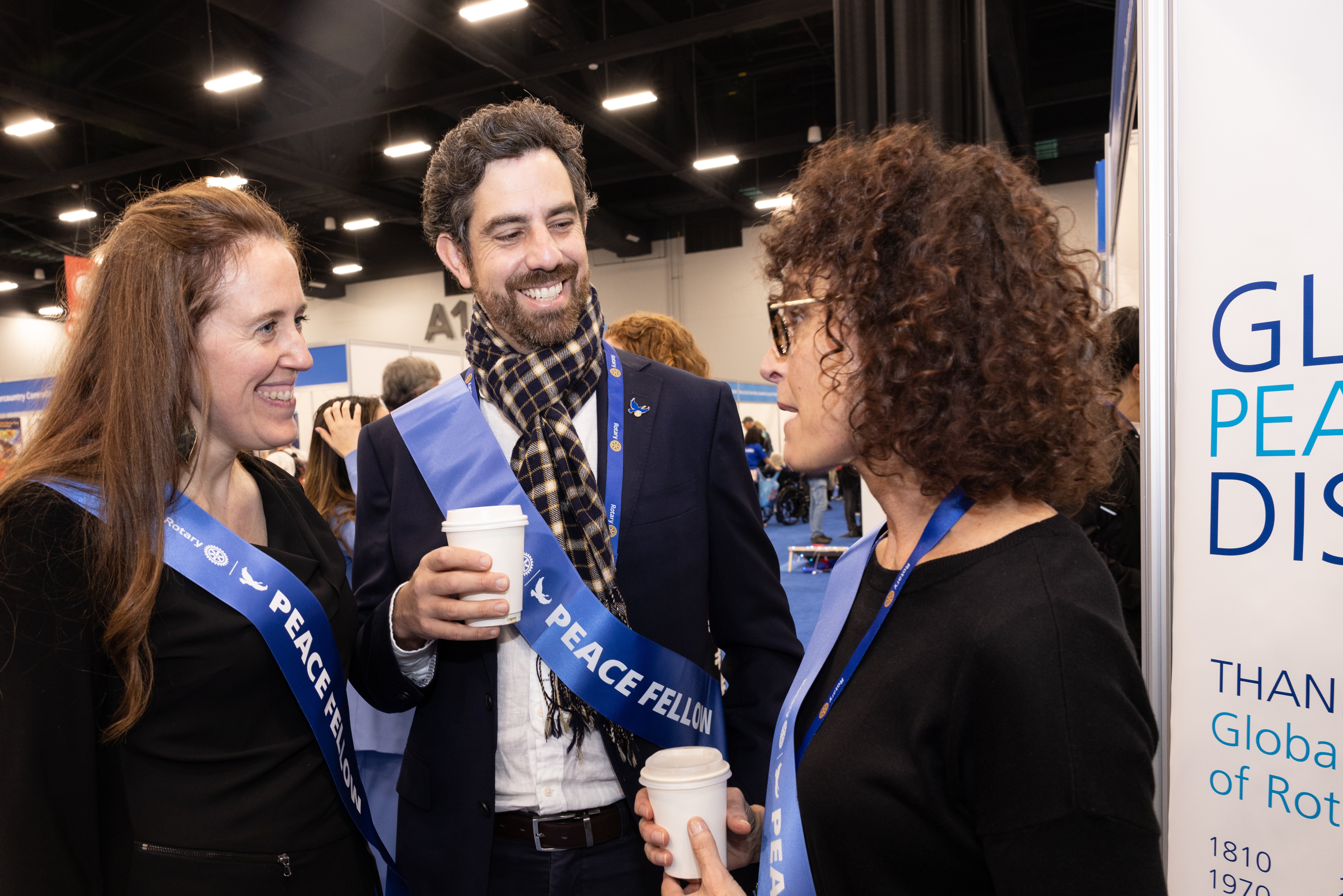 Peace fellows talk at the House of Friendship during the 2025 Rotary International Convention in Calgary, surrounded by project and fellowship displays