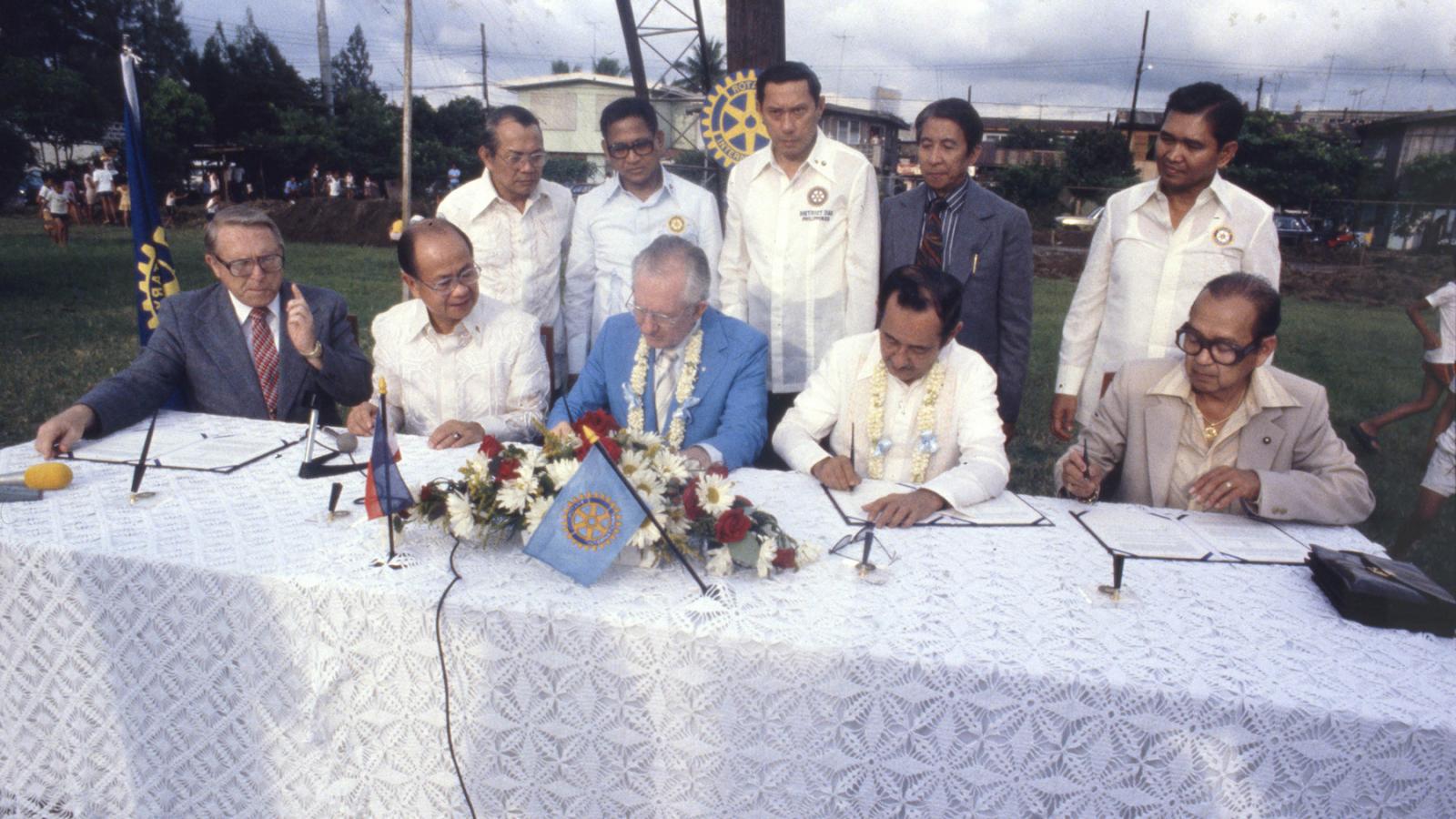 Representatives from Rotary International and the government of the Philippines are at a table to sign the agreement that starts Rotary International’s first polio project.