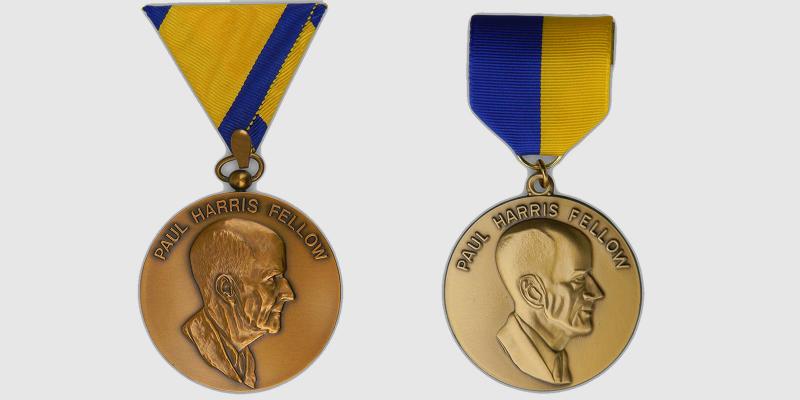 The first Paul Harris Fellow medallion, left, and a later version. Various lapel and neck ribbons were used with this medallion throughout the years.