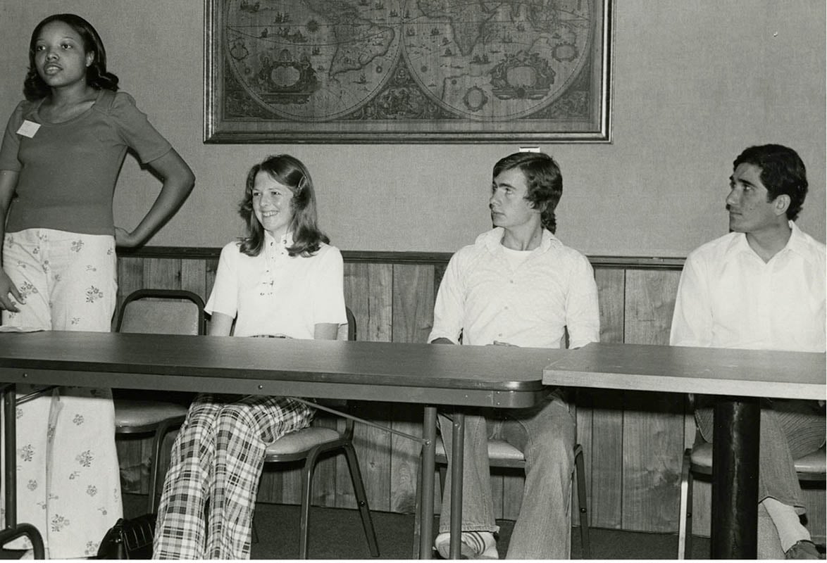 An Interactor from Sheffield, Alabama, USA, speaks at the Interact District 686 Conference. Other panelists represent clubs in the United States, New Zealand, England, and Cyprus. 1974.