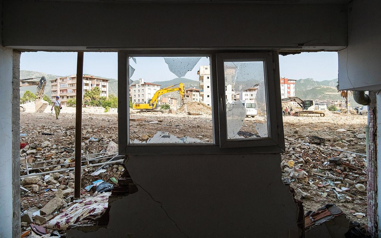 View through a damaged building in Turkey toward rubble and excavation equipment outside.