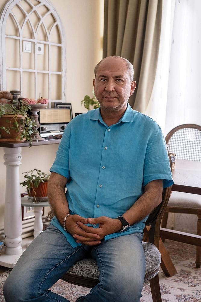 Rotary member Ferit Binzet seated in a chair in a living room.