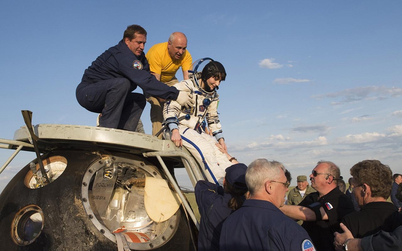 Cristoforetti, vestida con un traje espacial, recibe ayuda para salir de la cápsula de la nave espacial tras el aterrizaje.