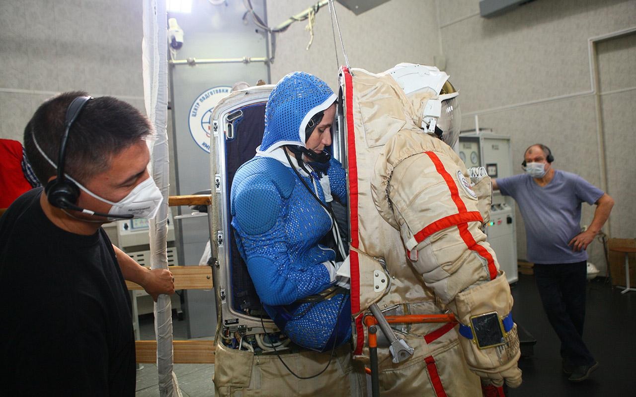 A Cristoforetti le están colocando un traje espacial durante el entrenamiento, mientras los técnicos supervisan el proceso.