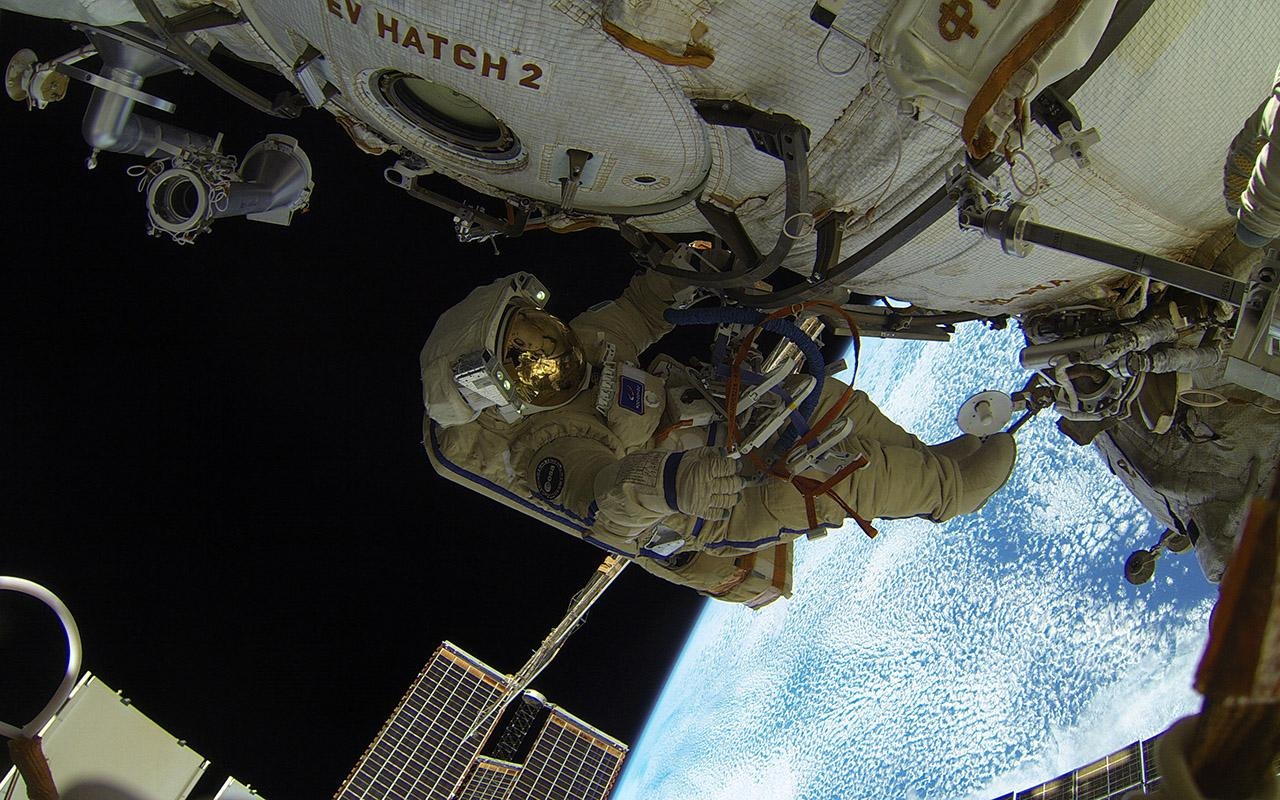 Cristoforetti realizando una caminata espacial fuera de la Estación Espacial Internacional, con la Tierra visible a sus pies.