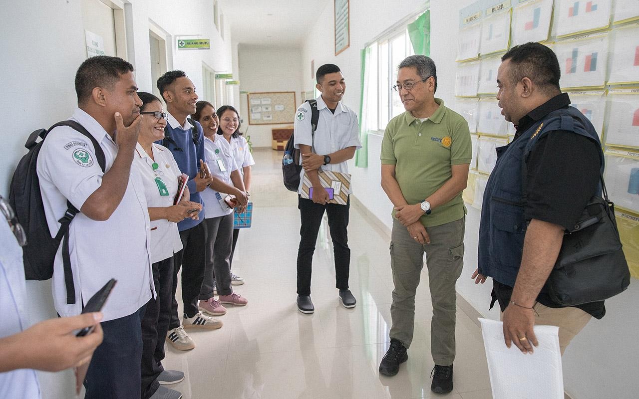 A member of The Rotary Foundation’s Cadre of Technical Advisers speaks with healthcare workers and local officials in a health facility hallway during a site visit.