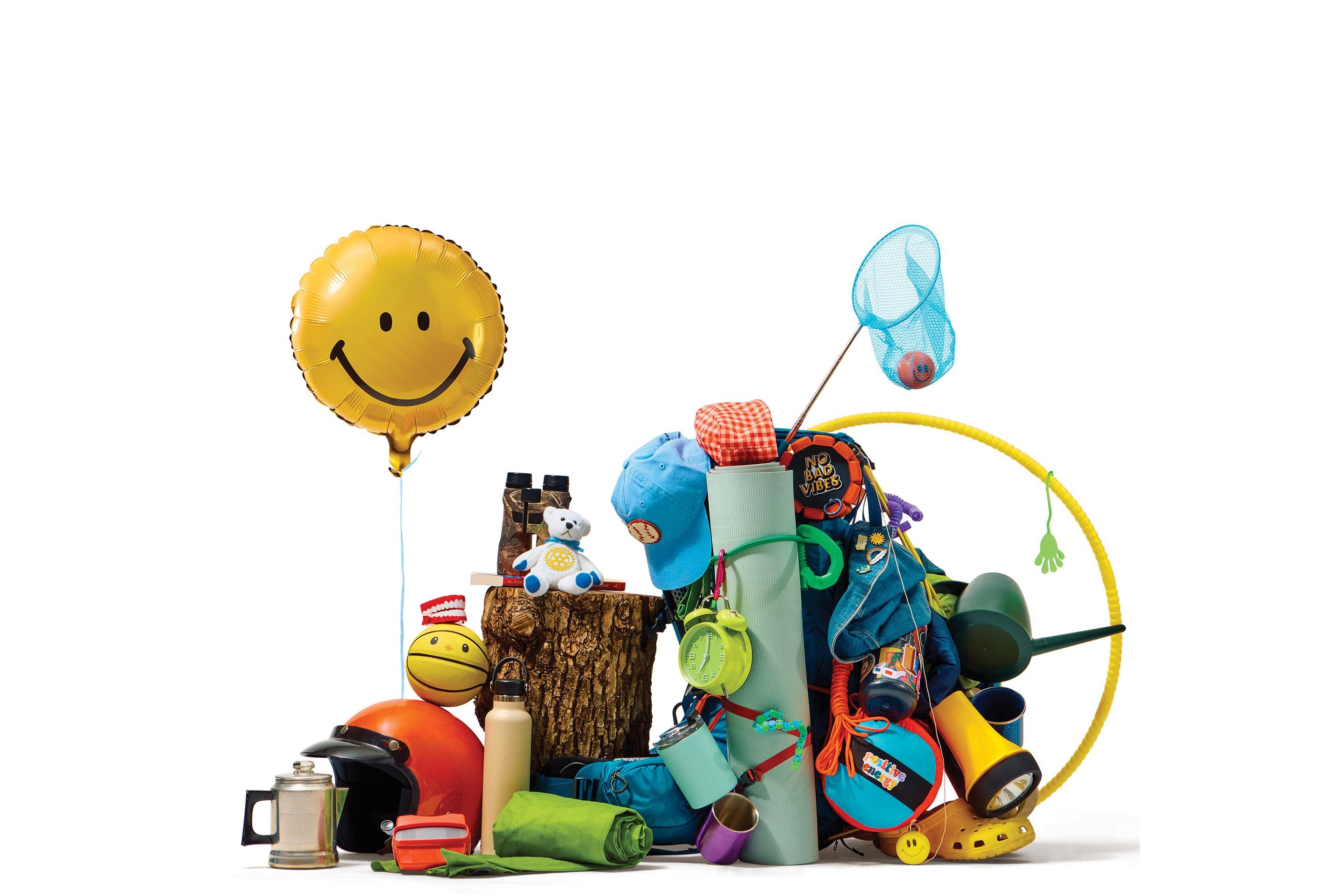 Smiley balloon above assorted toys, jump rope, blocks, and stuffed animals piled together