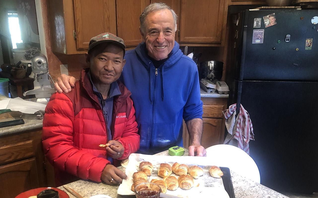 Die Rotarierin Michael Fels (rechts) und ihre Partnerin Jesada „Wee“ Simla stehen in einer Küche neben einem Tablett mit Croissants auf einer Arbeitsplatte