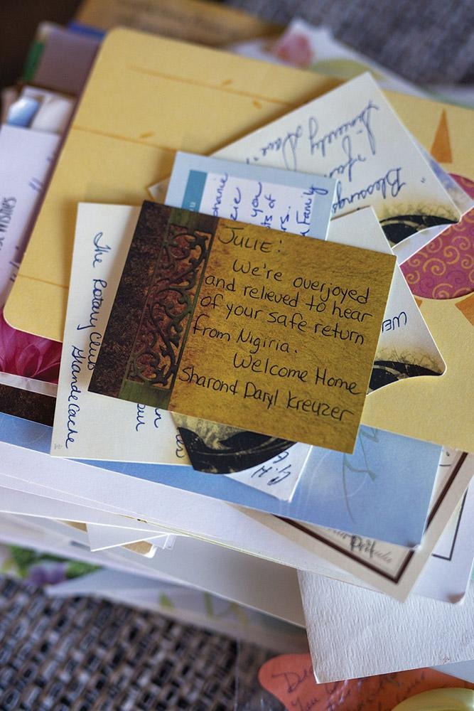Stack of handwritten letters, envelopes, and photographs with a note card placed on top containing handwritten text