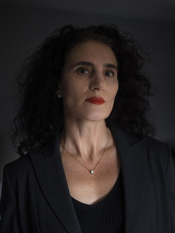 Attorney Susanna Southworth standing indoors near a window, wearing a dark jacket and necklace against a softly lit background