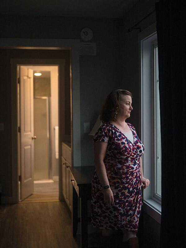 Rotary member Virginia McKenzie standing in a dimly lit room beside an illuminated doorway, looking toward the open door.