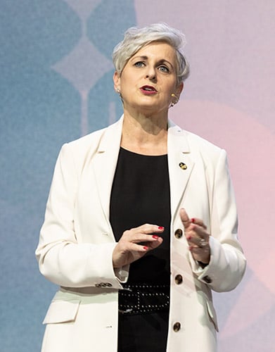 Valarie Wafer speaking on stage while gesturing with one hand and wearing a lapel microphone.