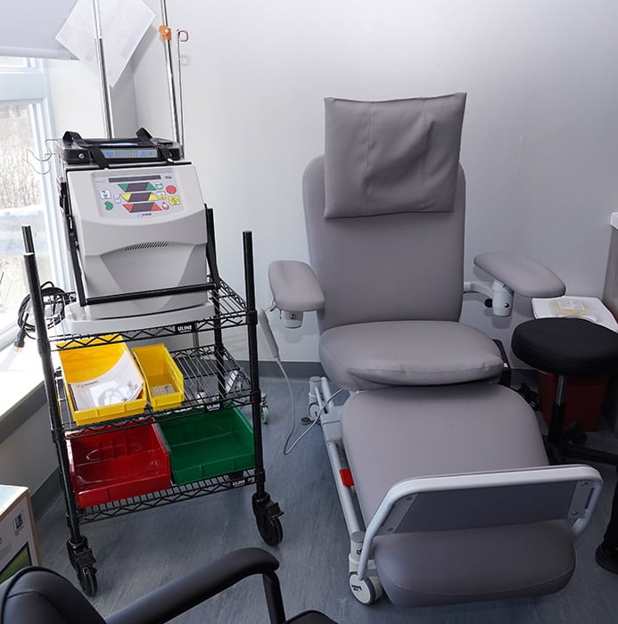 Sillón para exámenes médicos y carrito de suministros en un consultorio.