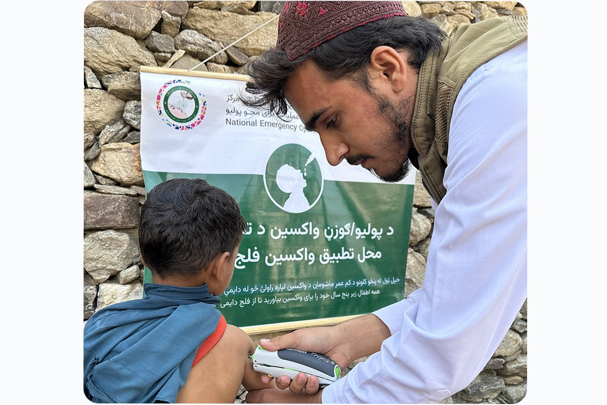 ahir Islam uses a needle-free jet injector to administer a polio vaccine to a child in eastern Afghanistan.