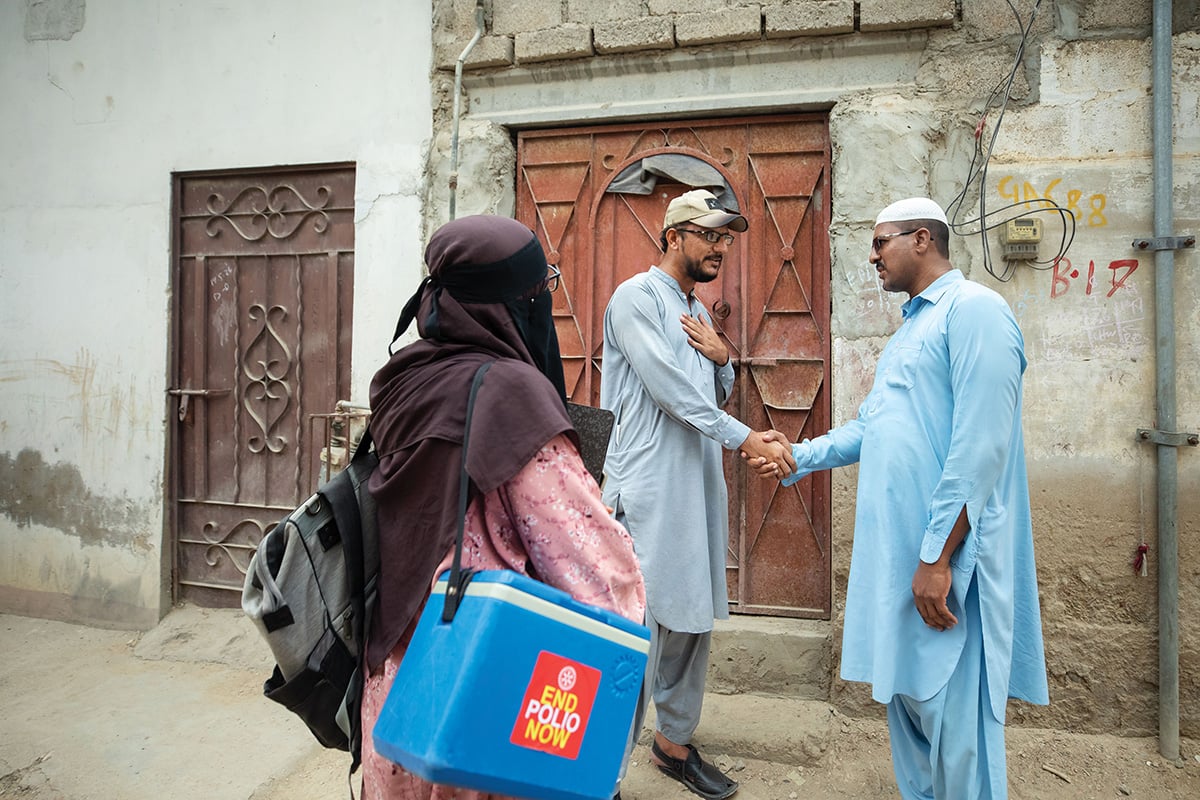 Healthcare workers greet each other outside a home