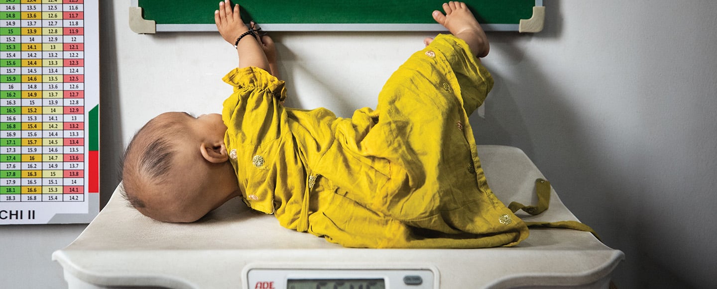 An infant lying on a doctor's scale